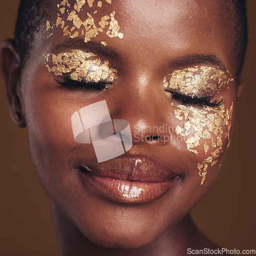 Image of Gold, creative and black woman with makeup for beauty aesthetics isolated in a studio brown background eyes closed. Art, luxury and face of African person with cosmetic glamour or design for skincare