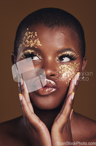 Image of Art, fun and black woman in gold makeup on brown background, glitter paint or cosmetics. Shine, glow and silly face of African model in studio for beauty, fashion and aesthetic freedom in luxury skin