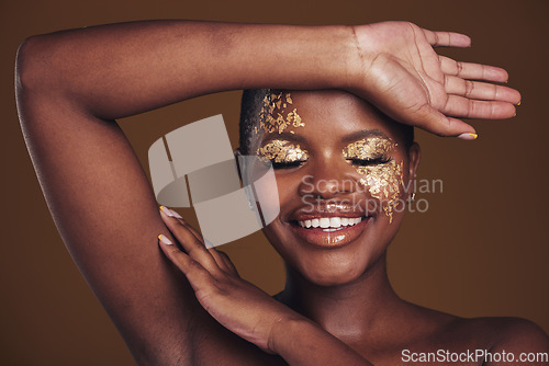 Image of Gold, creative and art on black woman with makeup for beauty aesthetics isolated in studio brown background eyes closed. Smile, luxury and face of person with cosmetic glamour or design for skincare