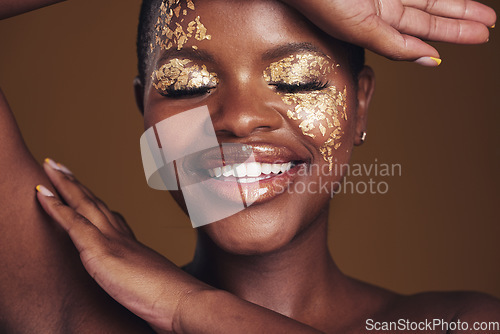 Image of Gold, creative and art on black woman face with makeup for beauty aesthetics isolated in a studio brown background. Smile, luxury and happy person with cosmetic glamour or design for skincare