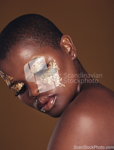 Image of Art, glitter and black woman with gold makeup on brown background, face paint and cosmetics. Shine, glow and African model in studio for beauty, fashion and aesthetic freedom in luxury skincare.