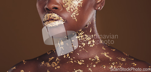 Image of Beauty, lips and black woman with gold makeup on brown background for art, cosmetics and glitter paint. Shine, glow and zoom on model mouth for aesthetic luxury, skincare and metal lipstick in studio