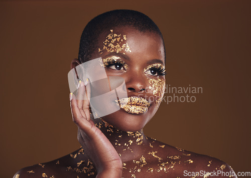 Image of Art, paint on black woman with gold makeup and brown background, glitter on face and cosmetics. Shine, glow and African model in studio for beauty, fashion and aesthetic freedom in luxury skincare