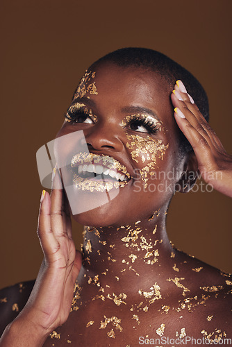 Image of Gold, glitter flake and black woman beauty with makeup and luxury in studio with sparkle cosmetics. Brown background, smile and female model with golden paint for skin glow and creative facial shine