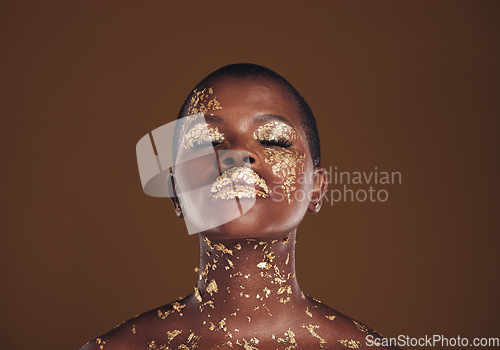 Image of Beauty, glitter and black woman with gold makeup on brown background with art, paint and cosmetics. Shine, glow and African model in studio for facial fashion, aesthetic freedom and luxury skincare.