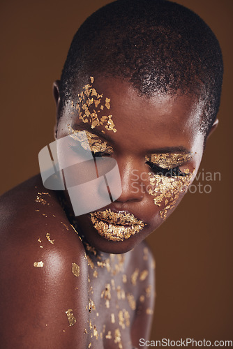 Image of Art, facial on black woman with gold makeup and brown background, glitter paint and cosmetics. Shine, glow and African model in studio for beauty, fashion and aesthetic freedom in luxury skincare.