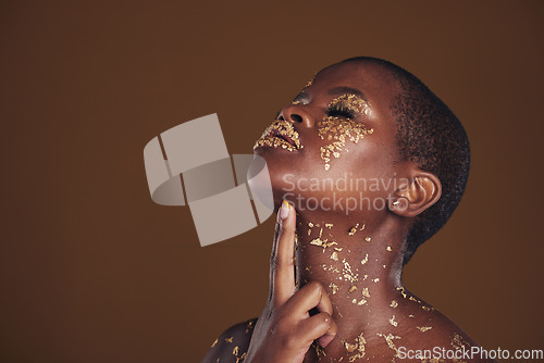 Image of Profile, beauty and black woman with gold makeup, mockup and brown background with art, glitter paint and cosmetics. Shine, glow and African model in studio space for aesthetic, luxury and skincare.