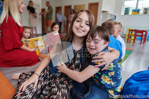 Image of A girl and a boy with Down's syndrome in each other's arms spend time together in a preschool institution