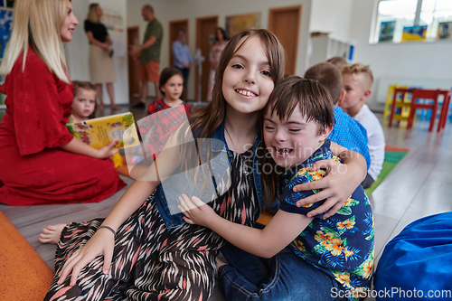 Image of A girl and a boy with Down's syndrome in each other's arms spend time together in a preschool institution