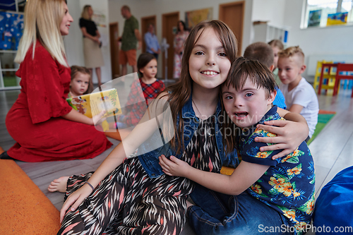 Image of A girl and a boy with Down's syndrome in each other's arms spend time together in a preschool institution
