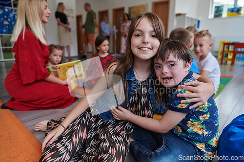 Image of A girl and a boy with Down's syndrome in each other's arms spend time together in a preschool institution