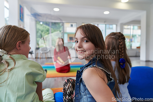 Image of Reading time in an elementary school or kindergarten, a teacher reading a book to children in an elementary school or kindergarten. The concept of pre-school education. Selective focus