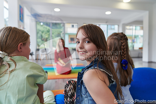 Image of Reading time in an elementary school or kindergarten, a teacher reading a book to children in an elementary school or kindergarten. The concept of pre-school education. Selective focus