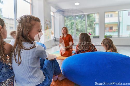 Image of Reading time in an elementary school or kindergarten, a teacher reading a book to children in an elementary school or kindergarten. The concept of pre-school education. Selective focus