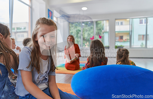 Image of Reading time in an elementary school or kindergarten, a teacher reading a book to children in an elementary school or kindergarten. The concept of pre-school education. Selective focus