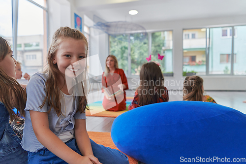 Image of Reading time in an elementary school or kindergarten, a teacher reading a book to children in an elementary school or kindergarten. The concept of pre-school education. Selective focus