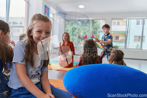 Image of Reading time in an elementary school or kindergarten, a teacher reading a book to children in an elementary school or kindergarten. The concept of pre-school education. Selective focus