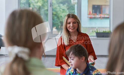 Image of Reading time in an elementary school or kindergarten, a teacher reading a book to children in an elementary school or kindergarten. The concept of pre-school education. Selective focus