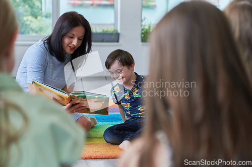 Image of Reading time in an elementary school or kindergarten, a teacher reading a book to children in an elementary school or kindergarten. The concept of pre-school education. Selective focus