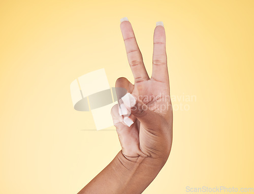 Image of Closeup, hands and peace sign with emoji, support and voice on a yellow studio background. Hand of female, person and model showing v symbol, icon or shape for hope, trust in vote and mockup space