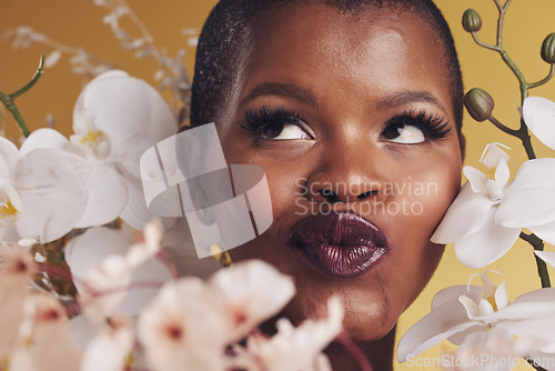 Image of Makeup, beauty and face of black woman with flowers for wellness, skincare and facial in studio. Spa, aesthetic and African person with orchids for natural cosmetics and glamour on yellow background