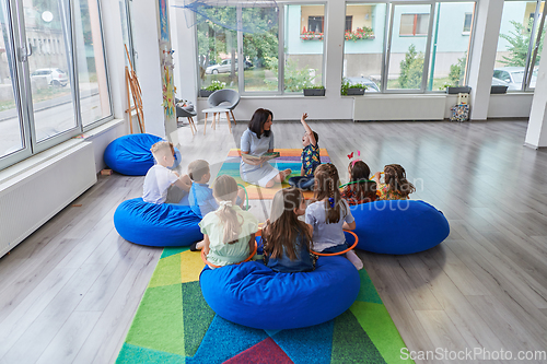 Image of Reading time in an elementary school or kindergarten, a teacher reading a book to children in an elementary school or kindergarten. The concept of pre-school education. Selective focus