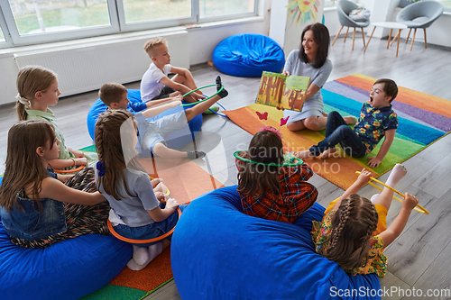 Image of Reading time in an elementary school or kindergarten, a teacher reading a book to children in an elementary school or kindergarten. The concept of pre-school education. Selective focus