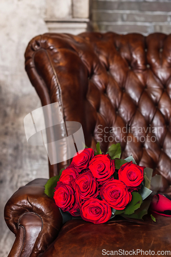 Image of Bouquet Of Red Roses On An Old Leather Armchair