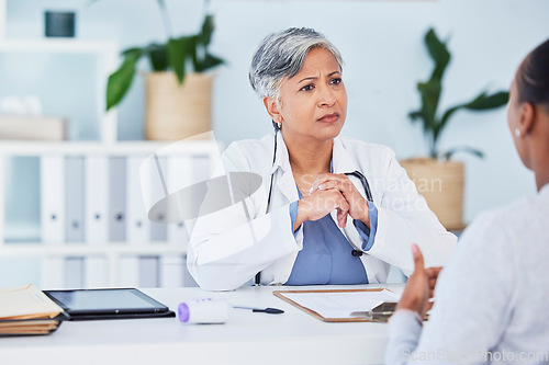 Image of Doctor, serious woman and office in consultation, support and services, helping or medical advice. Nurse or senior expert listening to patient history or healthcare, consulting and clinic information