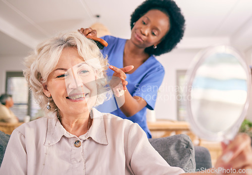 Image of Caregiver brush hair of happy senior woman in the living room of the modern retirement home for self care. Mirror, routine and African female nurse doing a hairstyle for an elderly patient in lounge.