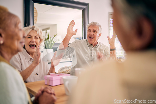 Image of Senior friends, birthday celebration and party at a home with a present and gift with excited people. Surprise, singing and retirement of elderly group at a dining room table together with a smile