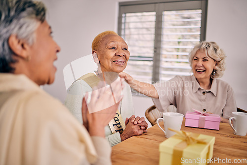 Image of Senior friends, birthday singing and party at a home with a present and gift with excited people. Surprise, celebration and retirement of elderly group at a dining room table together with a smile