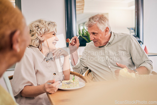 Image of Food, retirement and a senior couple in an assisted living home while eating a meal for nutrition. Cute, love or smile with a happy elderly man feeding his wife in the dining room of a house