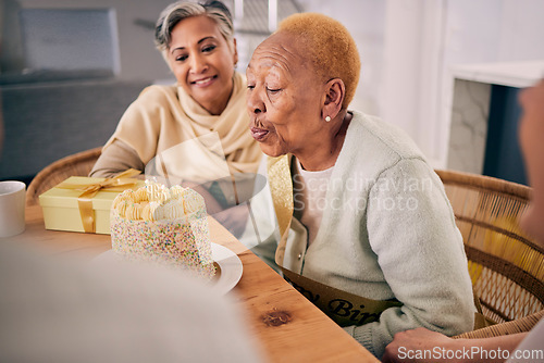 Image of Senior woman blowing candles on her cake for birthday celebration at a house at a party with friends. Smile, happy and elderly female person with a dessert to celebrate with people in retirement home