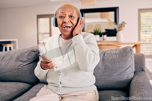 Image of Headphones, relax and portrait of senior woman on sofa in home listening to music, audio and radio. Retirement, technology and person in living room on phone for streaming track, song or subscription