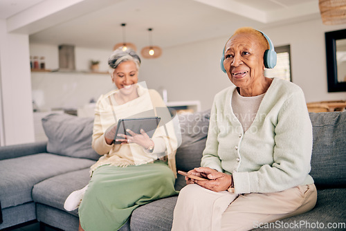 Image of Headphones, relax and senior women on sofa in home listen to music, audio and radio with friend. Retirement, technology and people in living room on tablet for streaming track, song or subscription