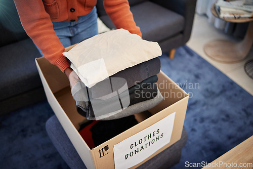 Image of Donation box, charity and hands with clothes for nonprofit and cardboard container at home. Moving, donating and house with giveaway and spring cleaning for community care support with packing