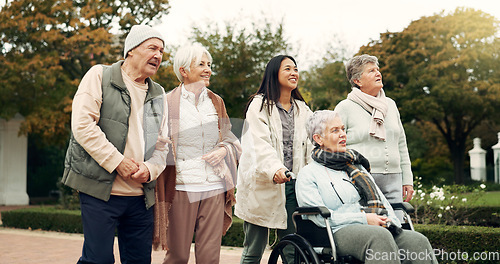 Image of Retirement, walking and senior friends in park for bonding, wellness and quality time together outdoor. Wheelchair, nature and elderly man and women with caregiver for fresh air, health and relax