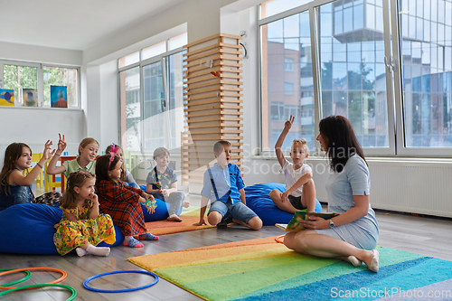 Image of Reading time in an elementary school or kindergarten, a teacher reads a book to children in an elementary school or kindergarten. The concept of pre-school education. Selective focus