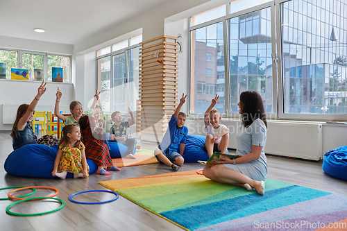 Image of Reading time in an elementary school or kindergarten, a teacher reads a book to children in an elementary school or kindergarten. The concept of pre-school education. Selective focus