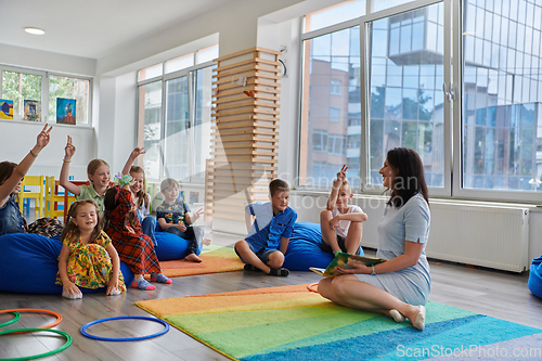 Image of Reading time in an elementary school or kindergarten, a teacher reads a book to children in an elementary school or kindergarten. The concept of pre-school education. Selective focus