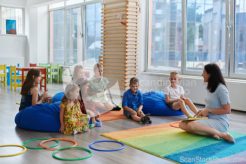 Image of Reading time in an elementary school or kindergarten, a teacher reads a book to children in an elementary school or kindergarten. The concept of pre-school education. Selective focus