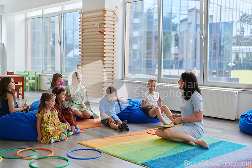 Image of Reading time in an elementary school or kindergarten, a teacher reads a book to children in an elementary school or kindergarten. The concept of pre-school education. Selective focus