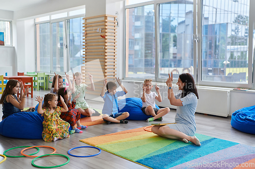 Image of Reading time in an elementary school or kindergarten, a teacher reads a book to children in an elementary school or kindergarten. The concept of pre-school education. Selective focus