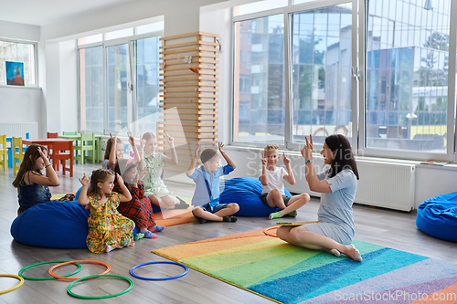 Image of Reading time in an elementary school or kindergarten, a teacher reads a book to children in an elementary school or kindergarten. The concept of pre-school education. Selective focus