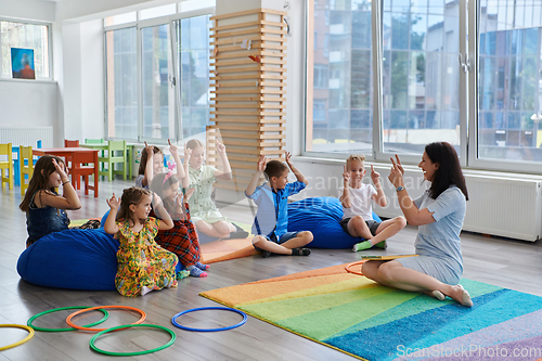 Image of Reading time in an elementary school or kindergarten, a teacher reads a book to children in an elementary school or kindergarten. The concept of pre-school education. Selective focus