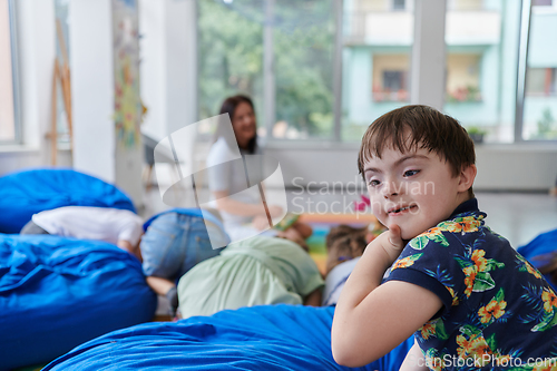 Image of A happy female teacher sitting and playing hand games with a group of little schoolchildren