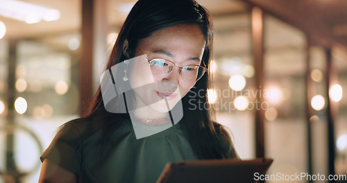 Image of Woman, tablet and reading in night at office, focus or happy for social media app, chat or email. Asian web expert, digital marketing and working on strategy, tech business or social network in Tokyo