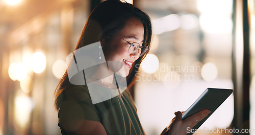 Image of Asian woman, tablet and typing in night office while working on project deadline. Digital tech, touchscreen and happy business woman working late in dark workplace, researching and writing email.