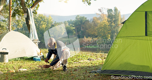 Image of Camping, tent and black man setup in woods for shelter on outdoor holiday, vacation and adventure, Campsite, traveling and male person with hammer for pins for gear in nature, forest and countryside